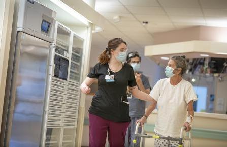 Photo of women walking down a hallway with helper.